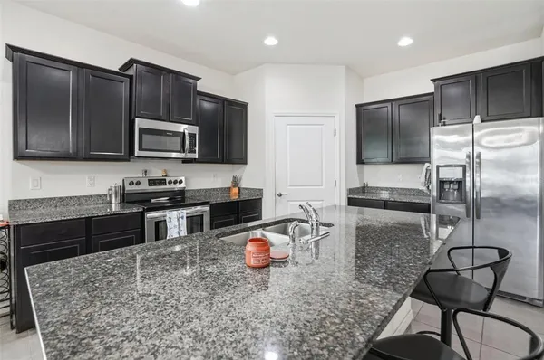 a kitchen with stainless steel appliances granite countertop a stove top oven a sink dishwasher a dining table and chairs with wooden floor