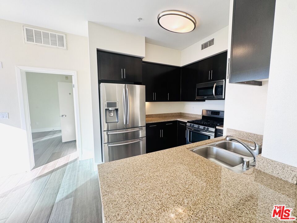 1241 5th Street, Unit 502 Santa Monica, CA 90401 - Photo 16 of 33 a kitchen with granite countertop a refrigerator and a sink
