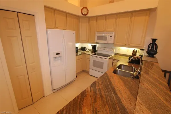 a kitchen with stainless steel appliances a refrigerator a sink a stove and white cabinets