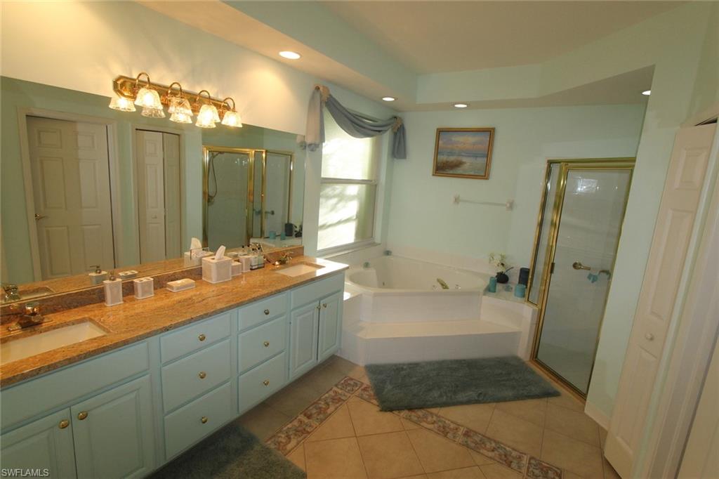 8526 Peppertree Way Naples, FL 34114 - Photo 10 of 14 a spacious bathroom with a double vanity sink a large mirror and shower