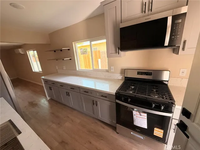 a kitchen with granite countertop a stove and a flat screen tv