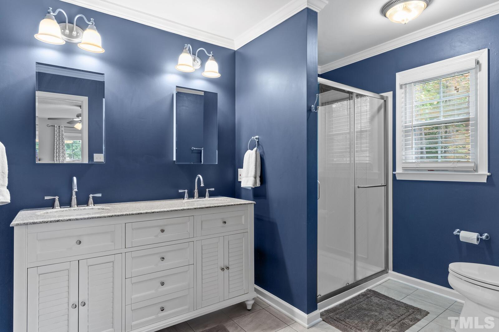 8312 Heel Stone Court Raleigh, NC 27613 - Photo 18 of 30 a bathroom with a double vanity sink a toilet and a mirror