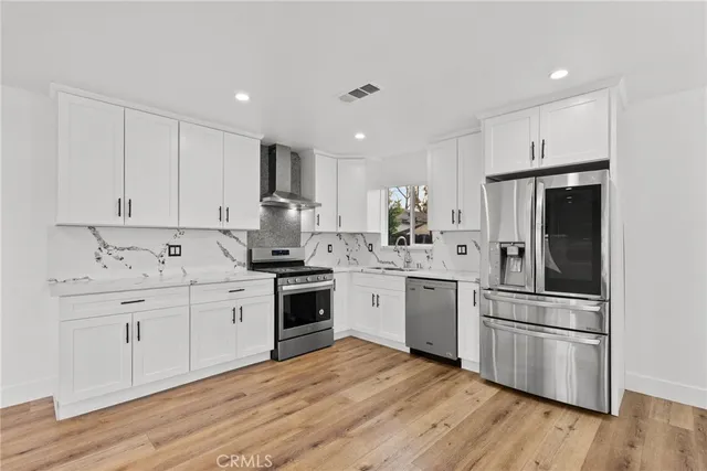 a kitchen with cabinets stainless steel appliances and wooden floor