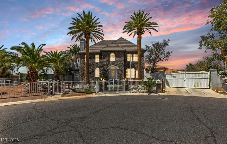 View of front of property featuring a gate, a fenced front yard, and stone siding
