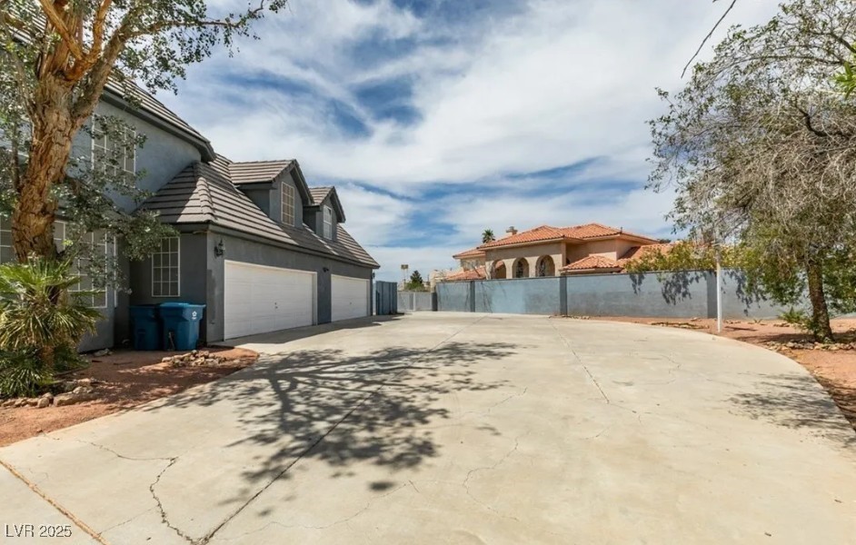 6520 Turtle Hill Road Las Vegas, NV 89110 - Photo 51 of 59 View of side of property featuring stucco siding, concrete driveway, a tiled roof, and an attached garage