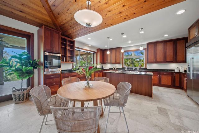 a kitchen with stainless steel appliances granite countertop a table chairs sink and window