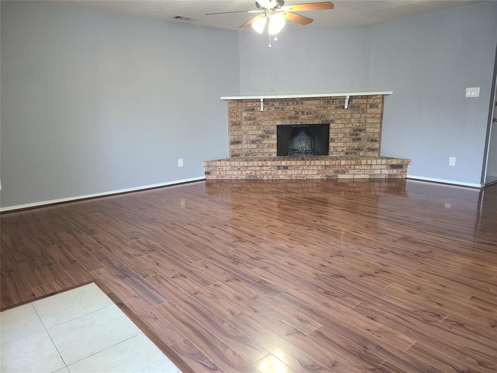 5644 Perrin Street The Colony, TX 75056 - Photo 2 of 16 Unfurnished living room featuring wood-type flooring, a brick fireplace, and ceiling fan