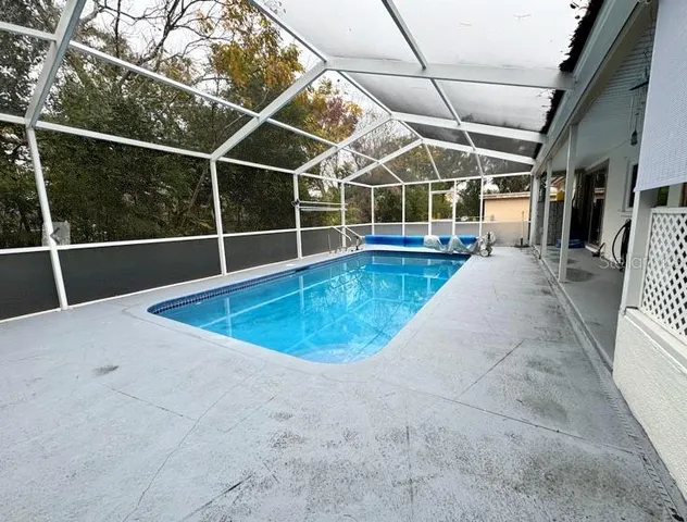 a view of a swimming pool with a yard and potted plants