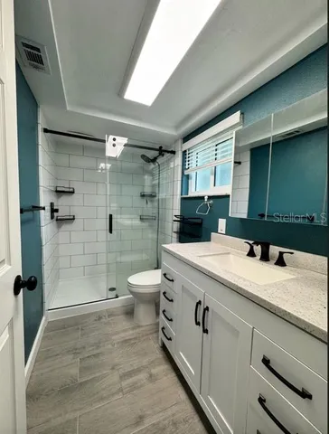 a bathroom with a granite countertop sink a toilet and shower