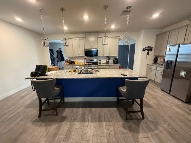 a kitchen with stainless steel appliances kitchen island granite countertop a table chairs sink refrigerator and microwave