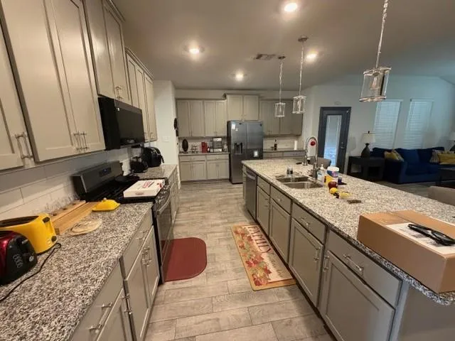 a kitchen with stainless steel appliances kitchen island granite countertop a sink stove and refrigerator