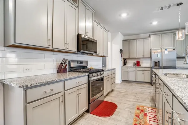 a kitchen with granite countertop kitchen island stainless steel appliances a sink stove top oven and cabinets