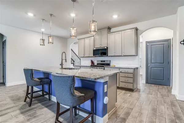 a kitchen with kitchen island granite countertop a table chairs microwave and cabinets