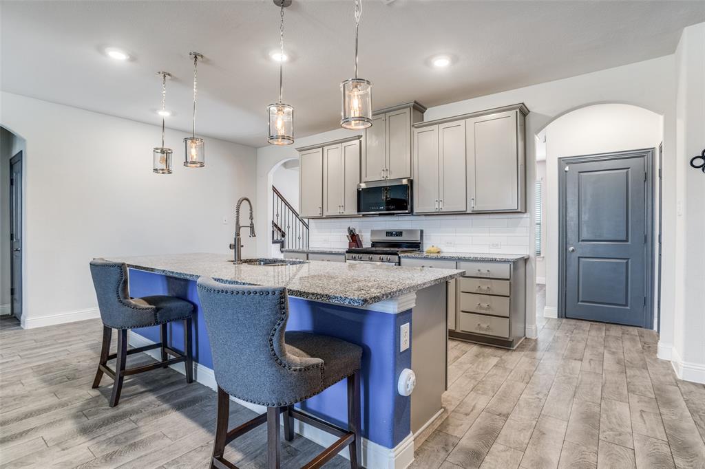 10421 Table Blf Street Aubrey, TX 76227 - Photo 6 of 25 a kitchen with kitchen island granite countertop a table chairs microwave and cabinets