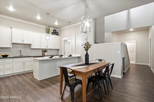 a kitchen with stainless steel appliances kitchen island granite countertop a dining table chairs and white cabinets