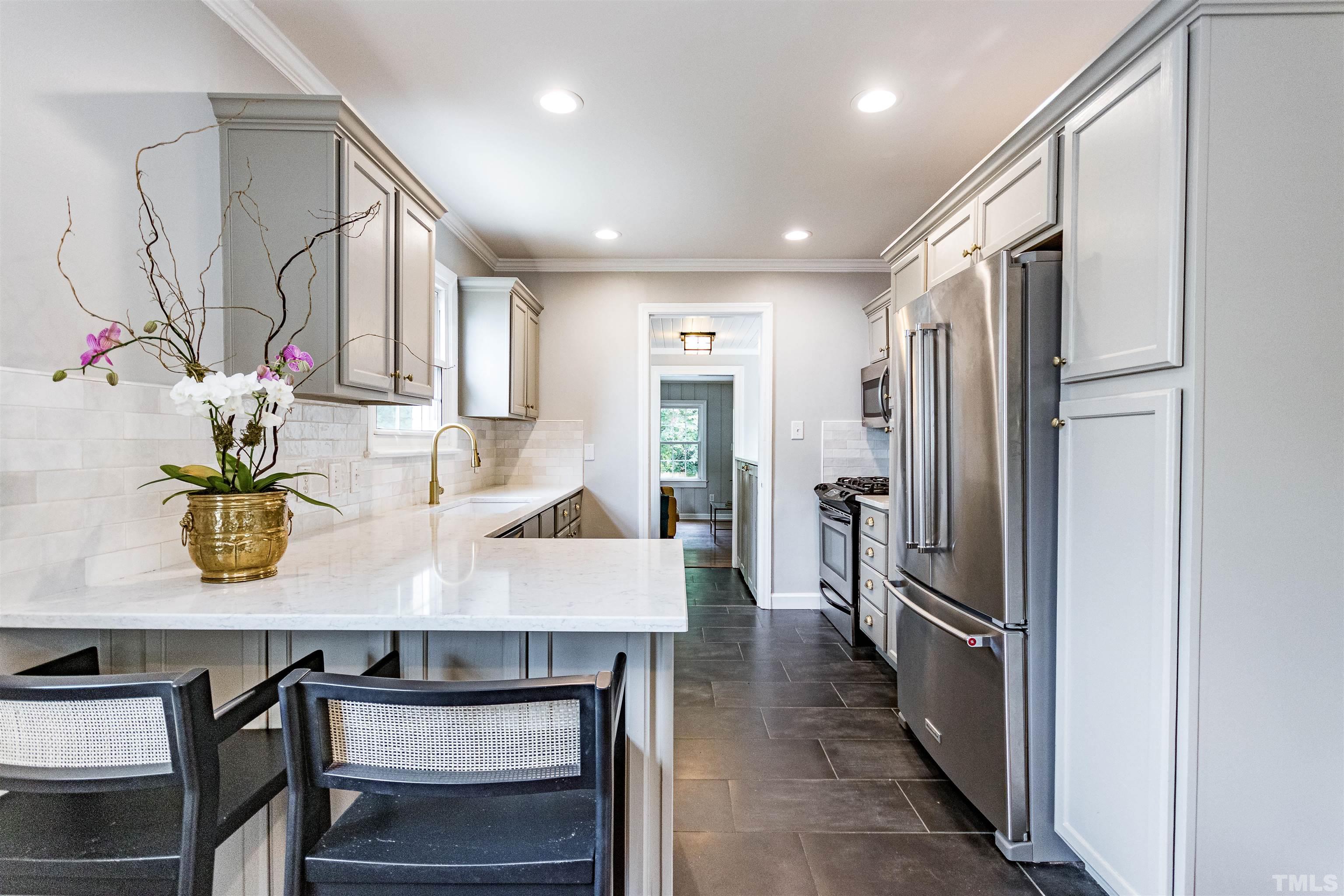 758 East Whitaker Mill Road Raleigh, NC 27608 - Photo 16 of 43 a kitchen with kitchen island a stove a refrigerator and a dining table
