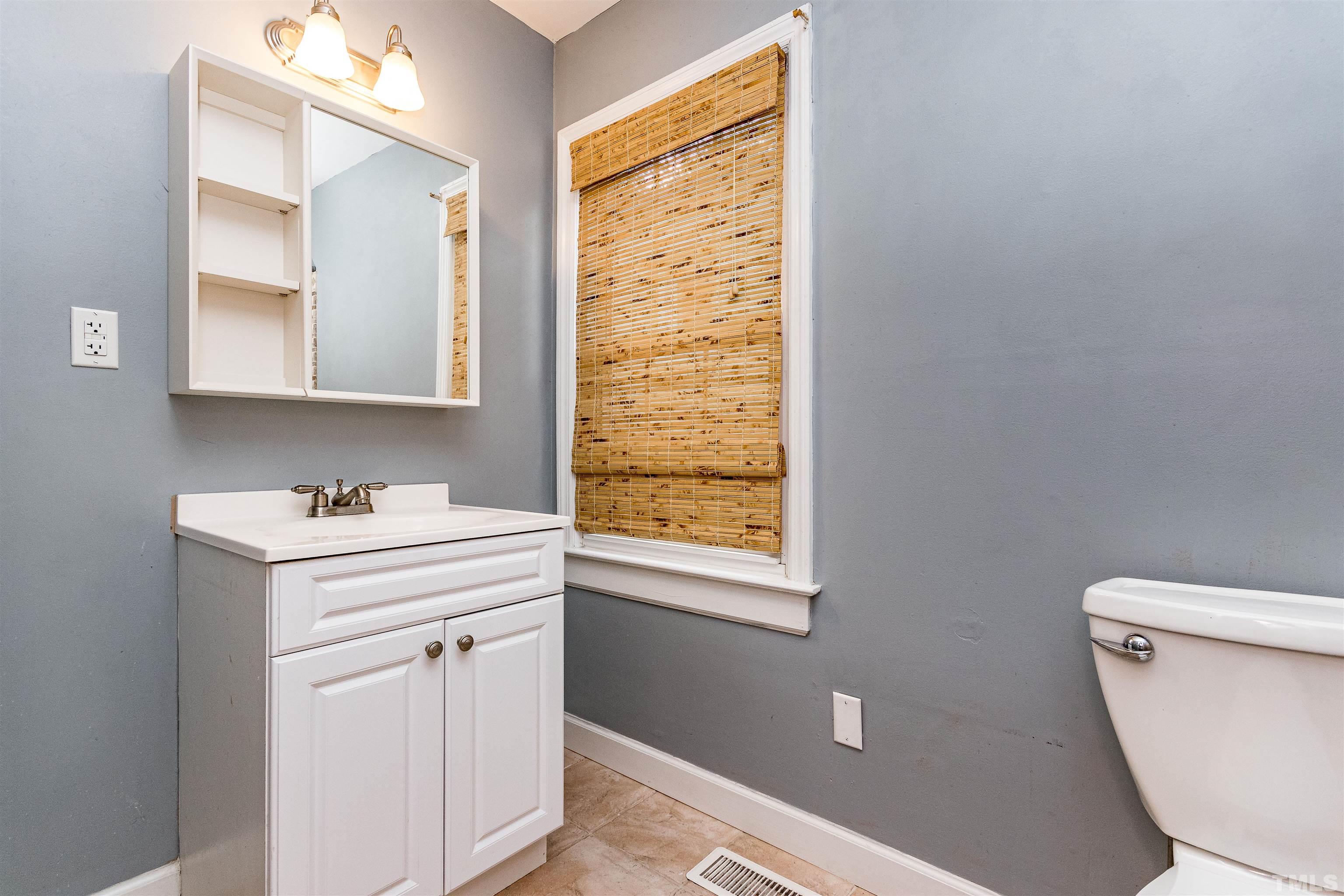 758 East Whitaker Mill Road Raleigh, NC 27608 - Photo 30 of 43 a bathroom with a sink a toilet and a mirror