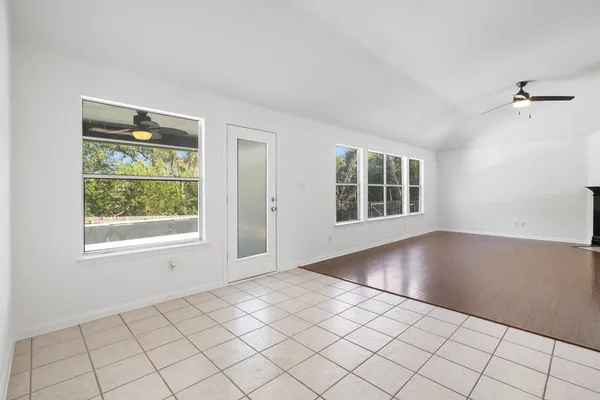 a view of an empty room with wooden floor fireplace and a window