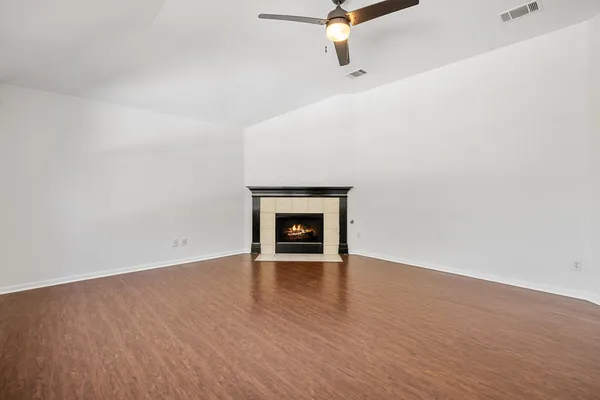 an empty room with wooden floor fireplace and windows