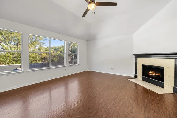 a view of empty room with wooden floor fireplace and window