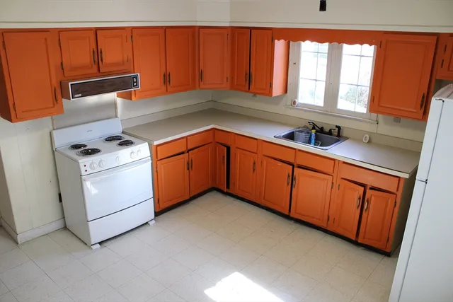 a kitchen with stainless steel appliances granite countertop wooden cabinets a sink a stove a washer and dryer
