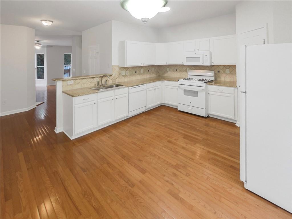 2225 Dillard Crossing Tucker, GA 30084 - Photo 17 of 41 a large kitchen with stainless steel appliances granite countertop a sink and cabinets with wooden floor
