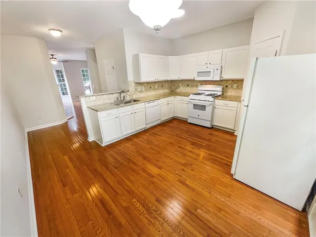 a kitchen with granite countertop white cabinets and white appliances
