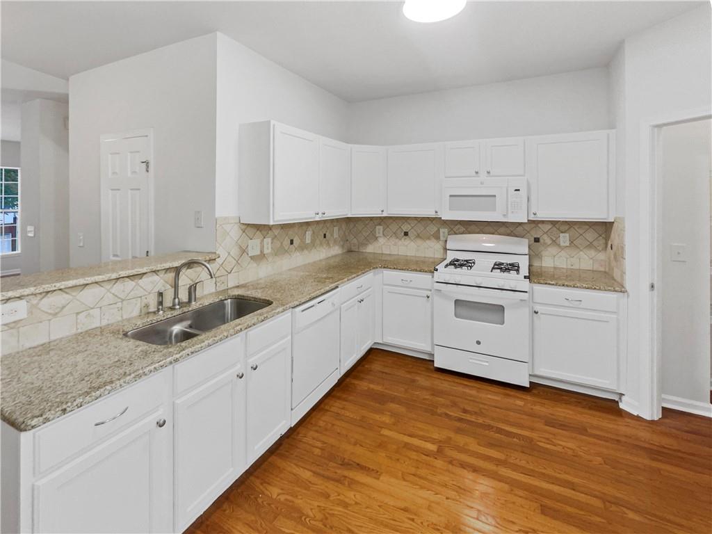 2225 Dillard Crossing Tucker, GA 30084 - Photo 4 of 41 a kitchen with granite countertop white cabinets and white appliances