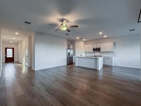 an empty room with wooden floor chandelier fan and windows