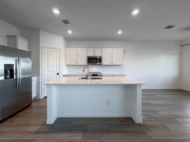 a kitchen with stainless steel appliances granite countertop a stove a sink and a refrigerator