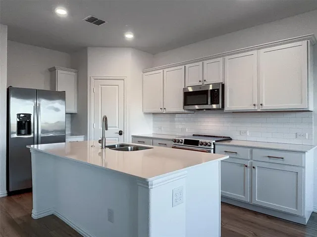 a kitchen with stainless steel appliances granite countertop a sink a stove a refrigerator and cabinets