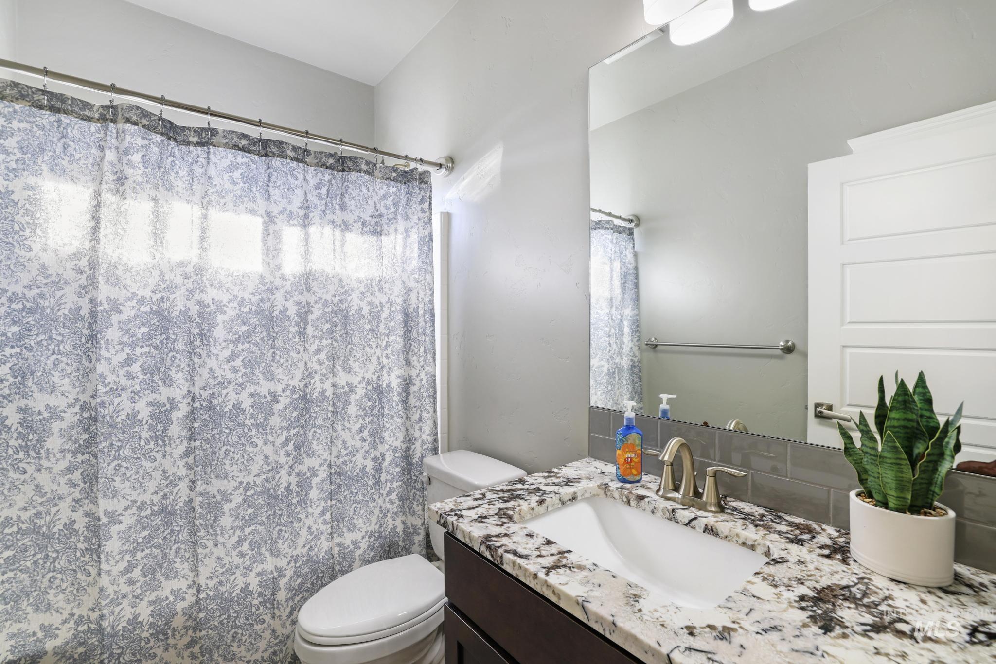 1050 Birchton Loop Twin Falls, ID 83301 - Photo 14 of 45 Bathroom featuring a dark wood-finish vanity with a drop-in sink, a speckled stone-finish countertop, and a gray subway tile backsplash