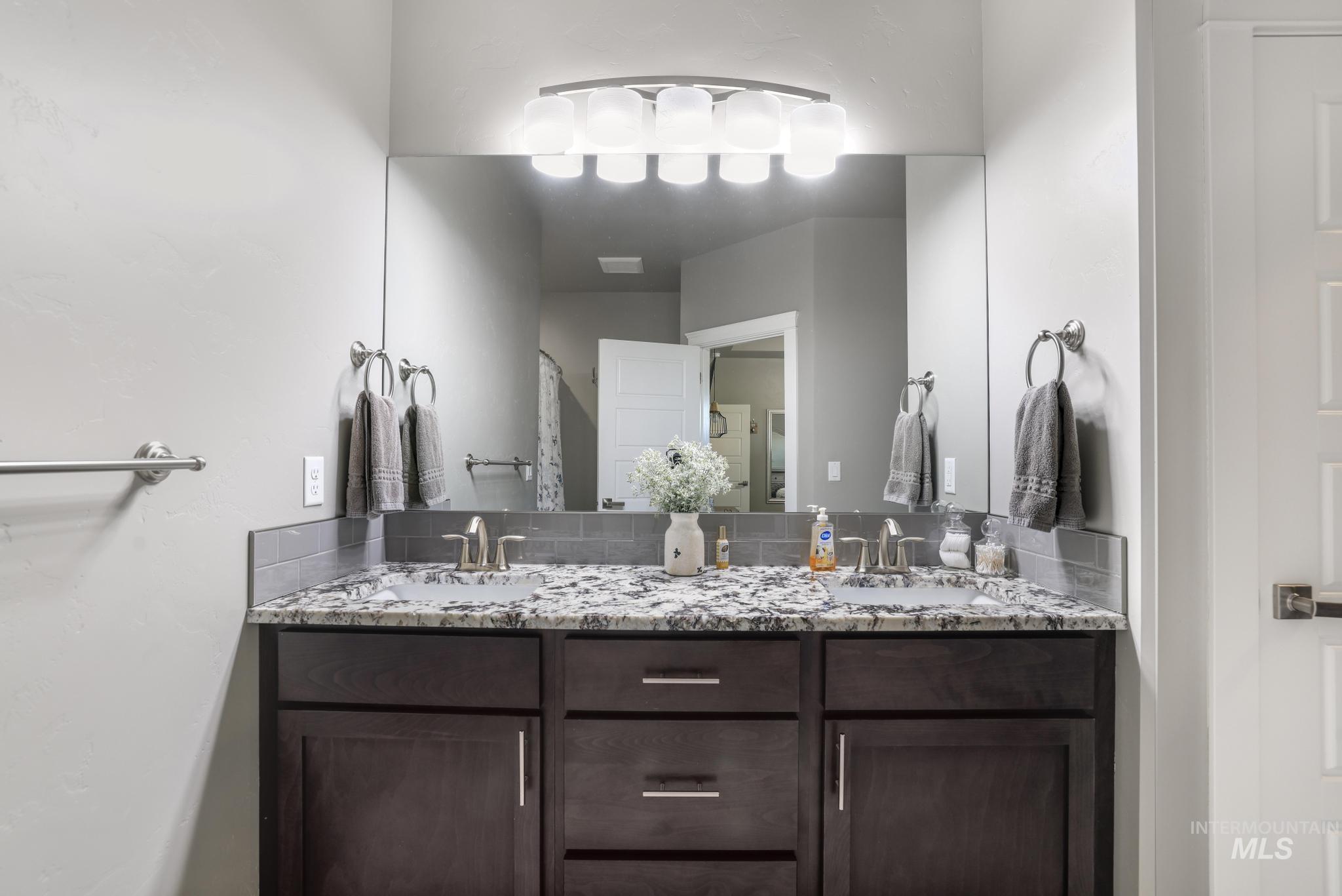 1050 Birchton Loop Twin Falls, ID 83301 - Photo 23 of 45 Dual vanity with undermount sinks, speckled countertop, dark wood-finish cabinetry, and brushed nickel hardware