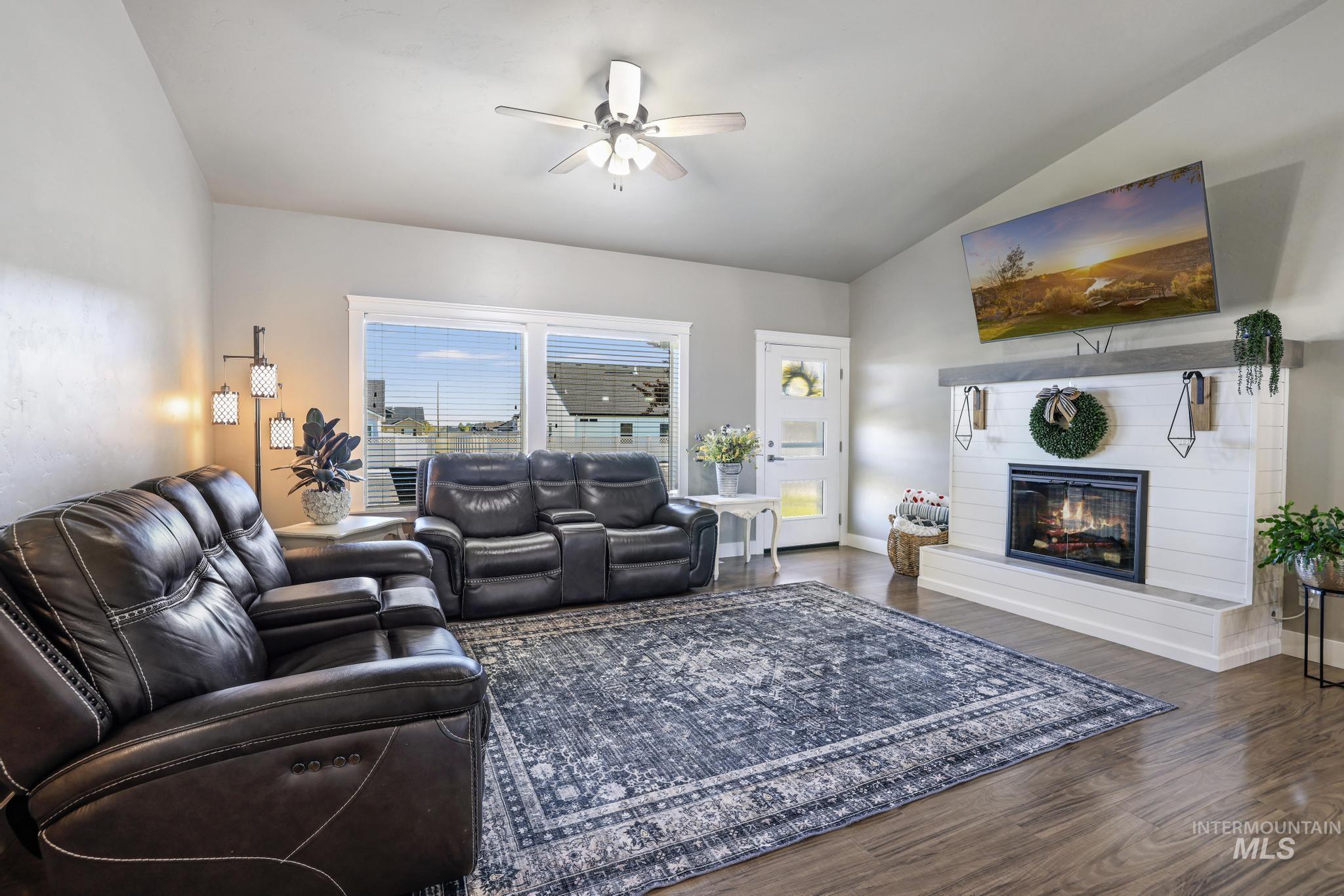 1050 Birchton Loop Twin Falls, ID 83301 - Photo 3 of 45 Living space featuring a shiplap fireplace with a wood-finish mantel, multiple windows, wood-finish flooring, a ceiling fan, and a light-colored door with frosted glass