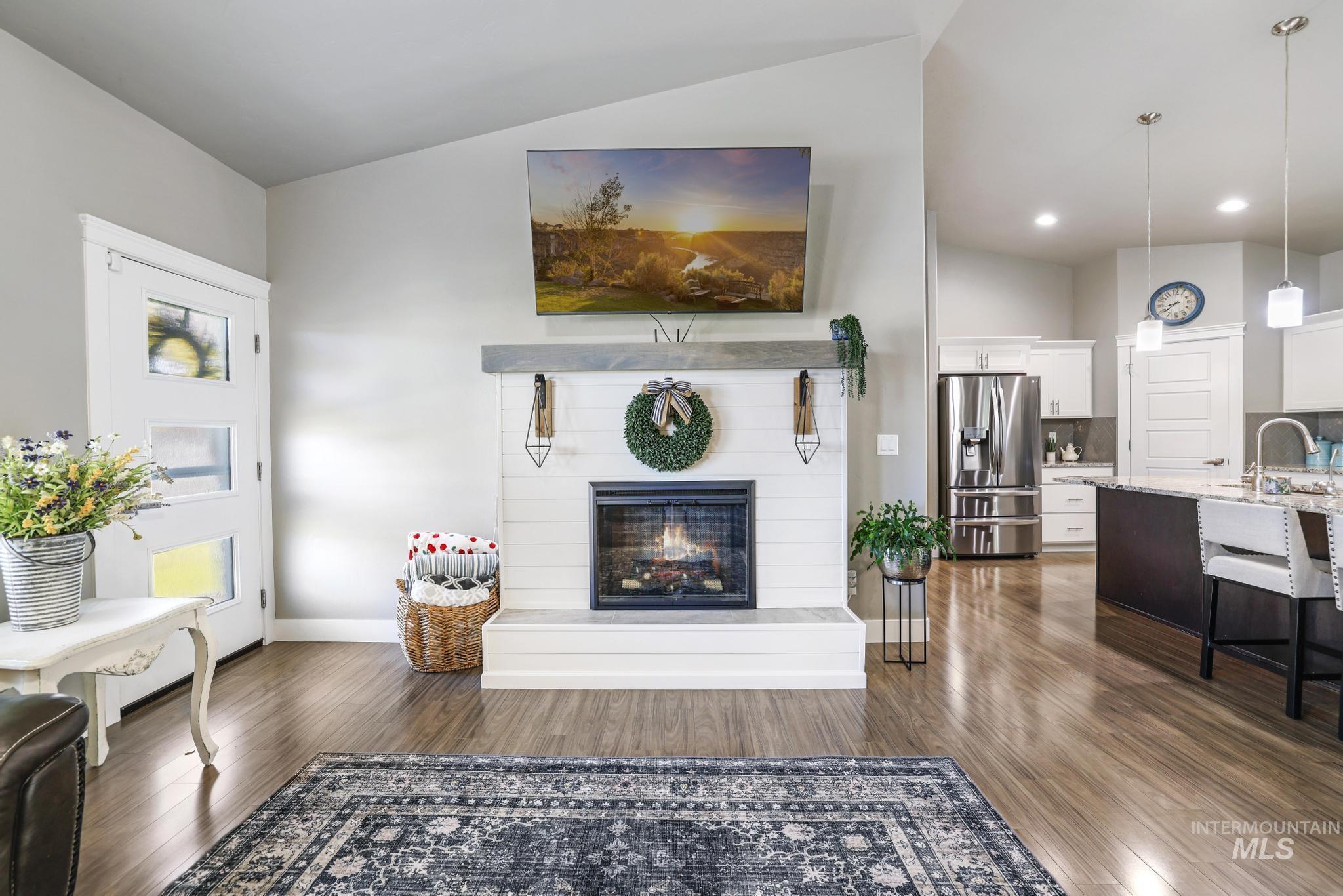 1050 Birchton Loop Twin Falls, ID 83301 - Photo 6 of 45 Living area featuring a fireplace with shiplap surround, wood-finish flooring, and vaulted ceilings