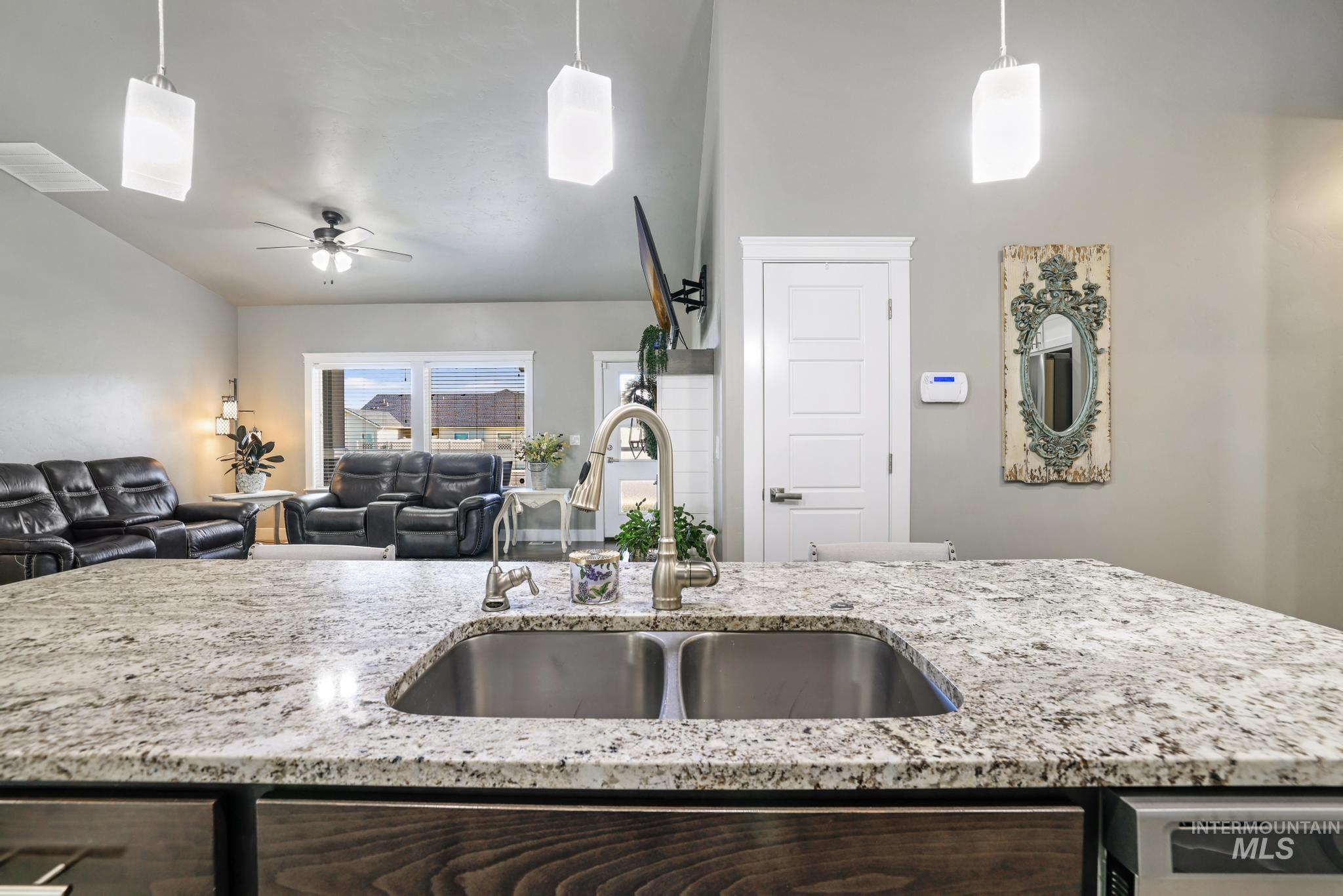 1050 Birchton Loop Twin Falls, ID 83301 - Photo 9 of 45 Kitchen island featuring a double basin stainless steel sink, gooseneck faucet, and speckled stone countertop