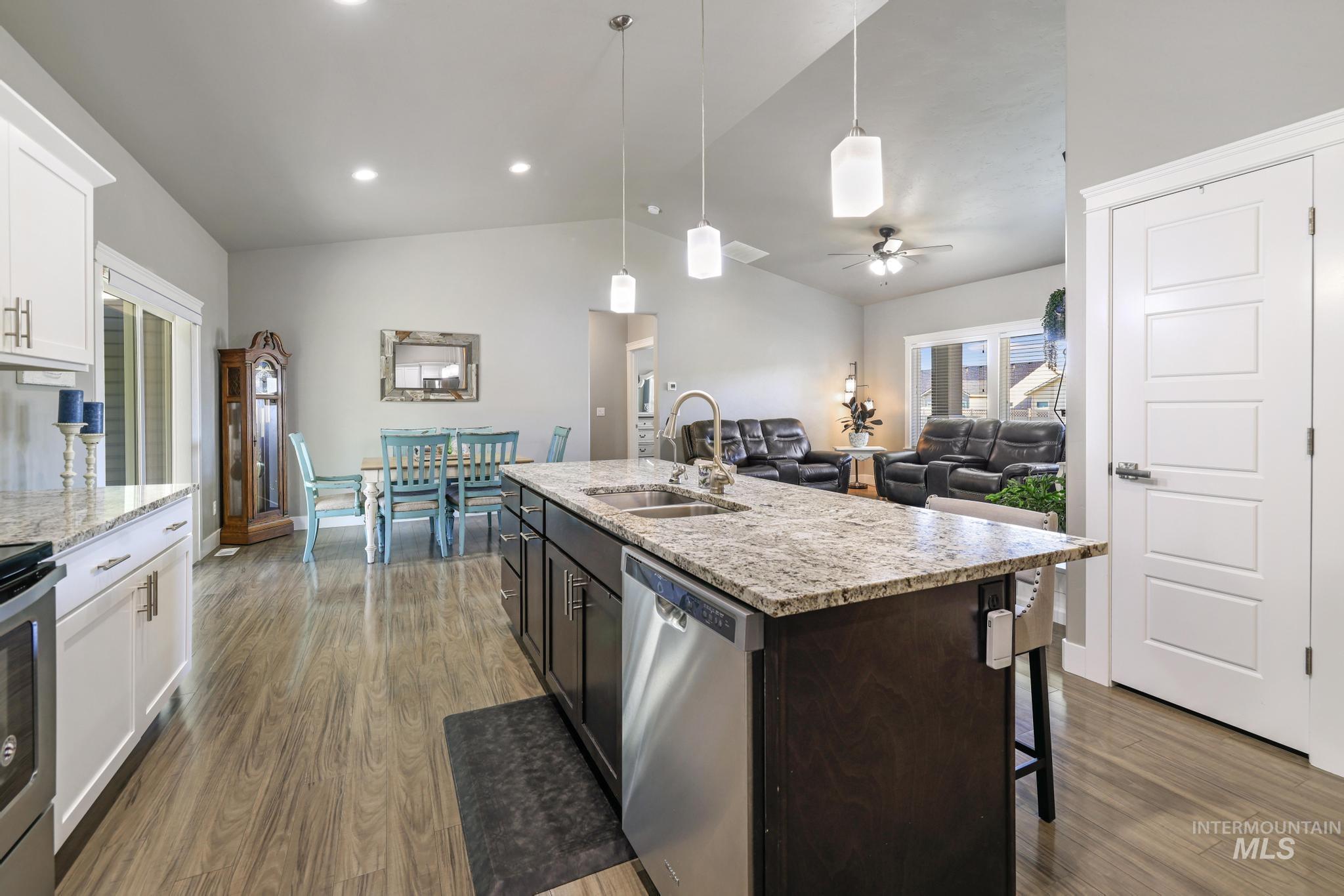 1050 Birchton Loop Twin Falls, ID 83301 - Photo 10 of 45 Open-concept living area featuring a kitchen island with granite countertops and pendant lighting, wood-finish flooring, white flat-panel cabinetry, and a ceiling fan