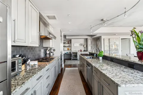 a kitchen with stainless steel appliances a lot of cabinets and wooden floor