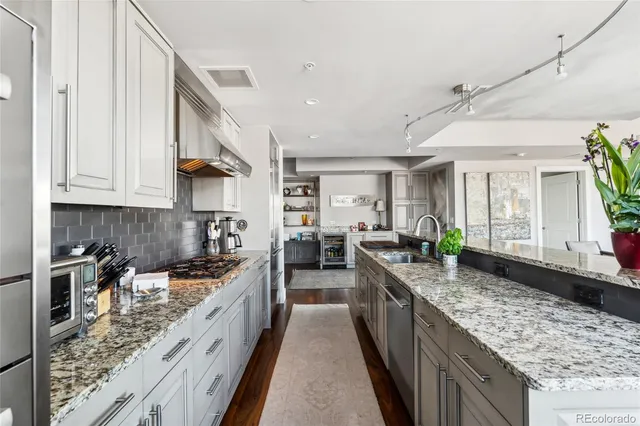 a kitchen with stainless steel appliances a lot of cabinets and wooden floor
