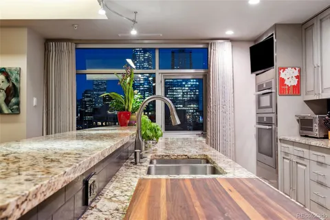 a view of a kitchen area with a granite counter top a potted plant on a counter and a sink