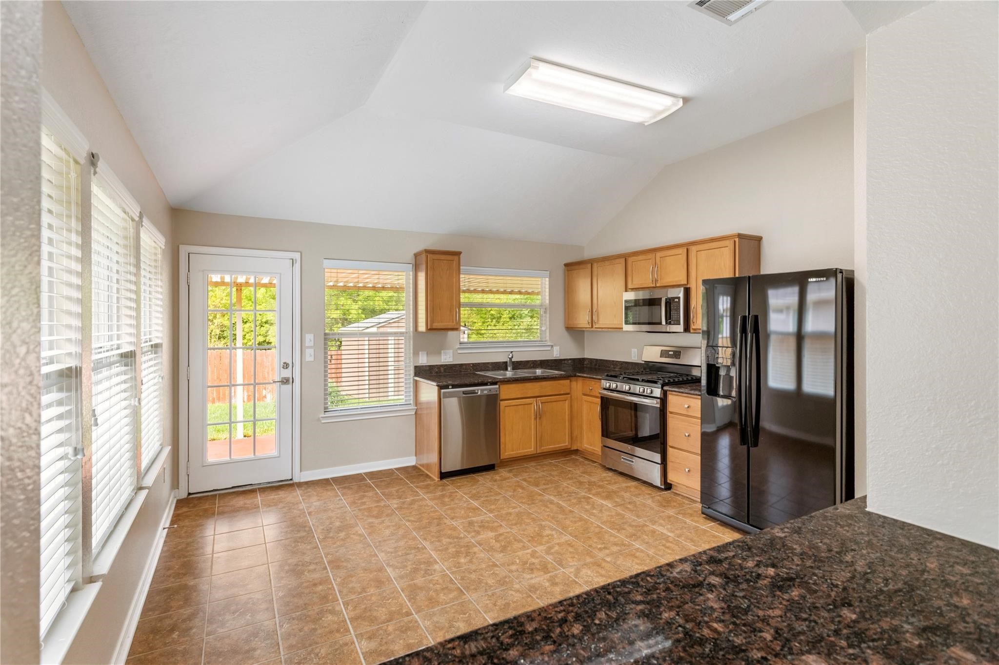 2023 Mountain Wind Loop Bryan, TX 77807 - Photo 7 of 16 a kitchen with stainless steel appliances granite countertop a stove a refrigerator and a sink