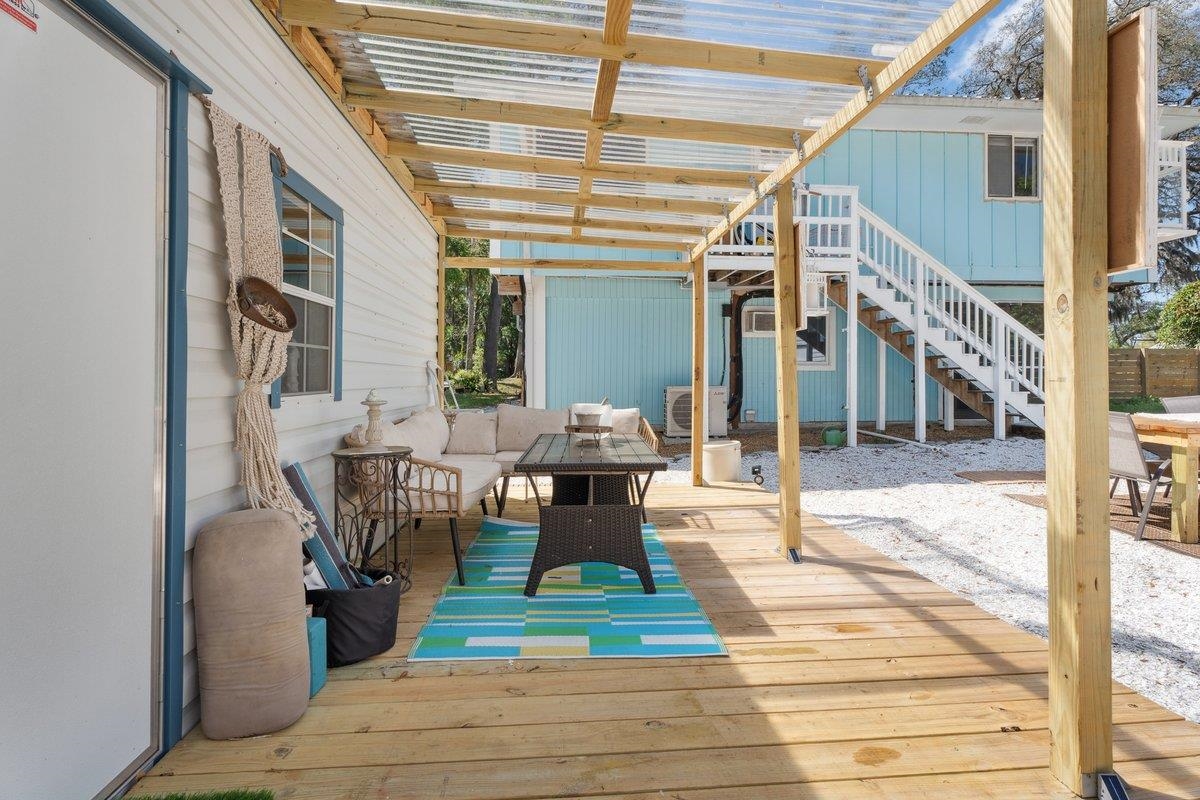 507 Gerona Road St. Augustine, FL 32086 - Photo 14 of 23 a view of a patio with table and chairs couches with wooden floor and fence