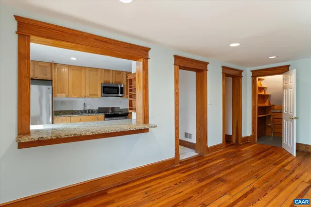 a view of a hallway with wooden floor and a bathroom