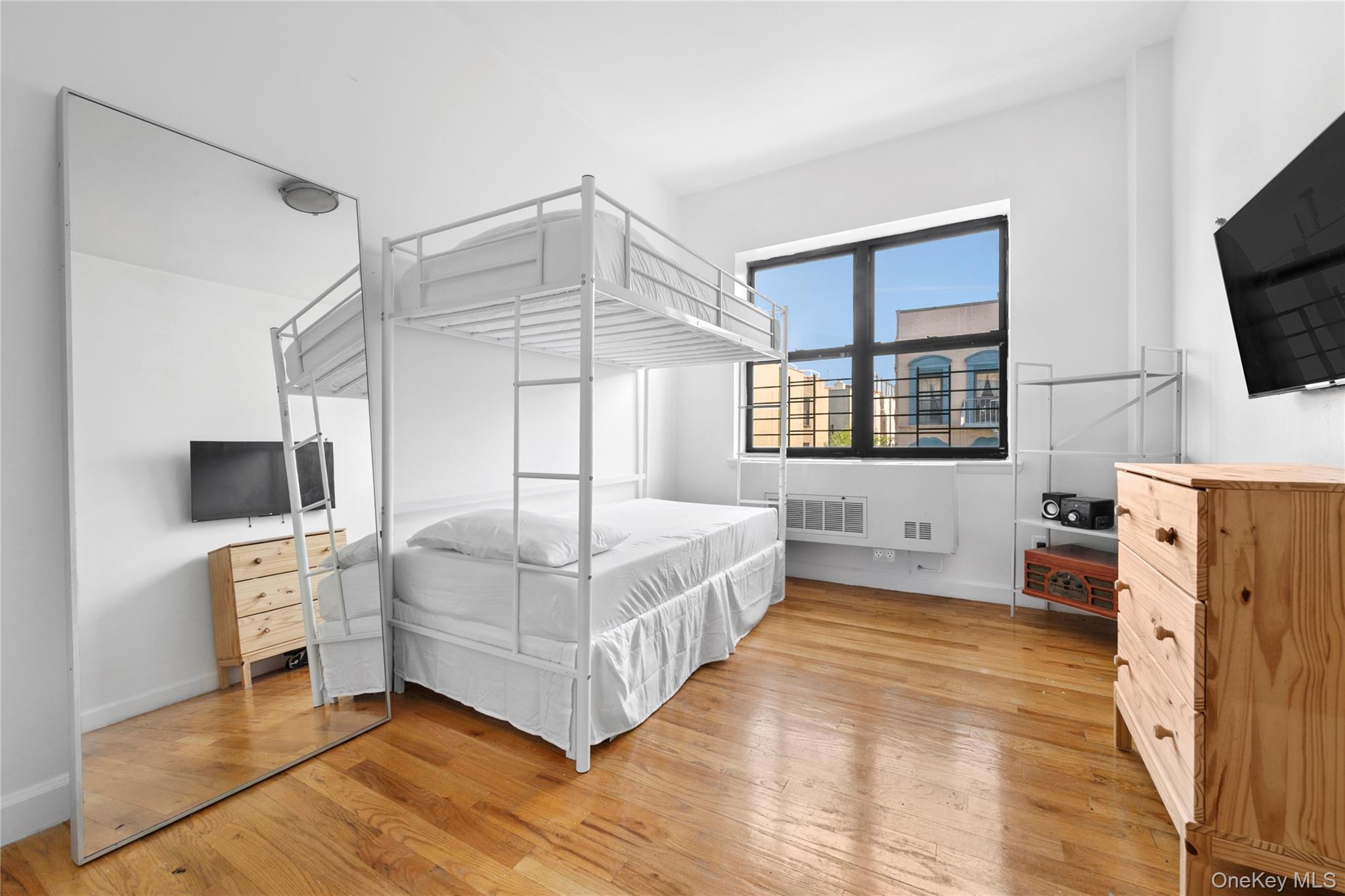 108 Odell Clark Place, Unit 5C Manhattan, NY 10030 - Photo 6 of 15 a bedroom with a bed a flat screen tv and a fireplace