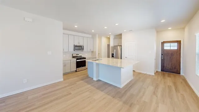 a large kitchen with kitchen island a sink wooden floor and stainless steel appliances