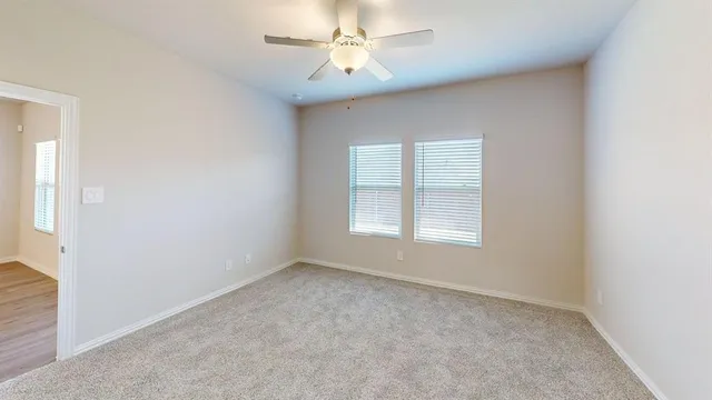 an empty room with a window and a fan