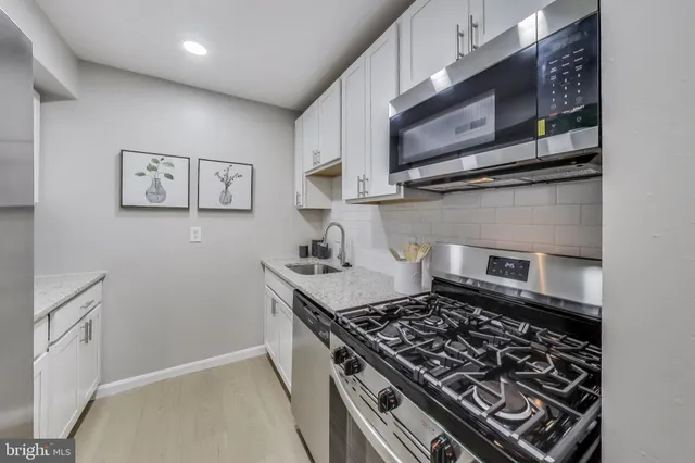 a kitchen with granite countertop a sink a stove and cabinets