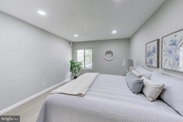 a spacious bedroom with a bed and painting on the wall