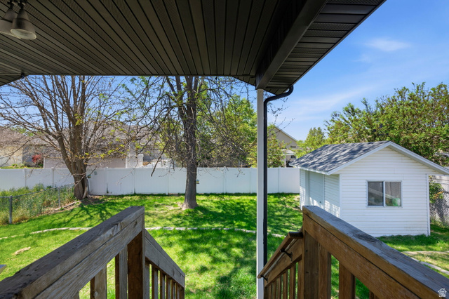 2460 Allison Way Syracuse, UT 84075 - Photo 22 of 24 Expansive backyard featuring a detached storage shed with a shingled roof, a white privacy fence, and mature trees