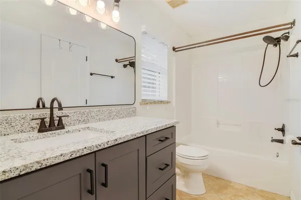 a bathroom with a granite countertop sink a toilet and shower